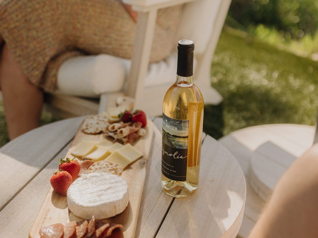 A wine and cheese display sits on a Seashell colored Bourbon Side table