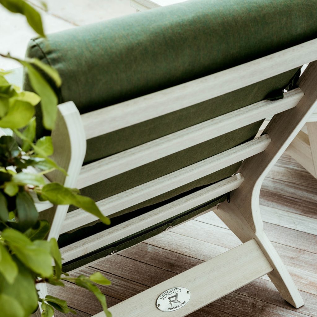 A Seashell Bourbon Chair with Fern Cushions sits on a patio, framework visible showing the craftsmanship of our furniture. 