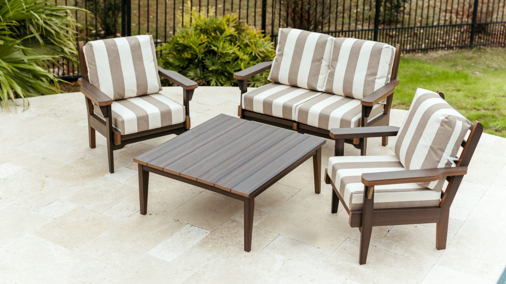 A loveseat, two chairs, and a coffee table sit on a pool patio. All poly furniture pieces have striped cushions made with Sunbrella Paxton.
