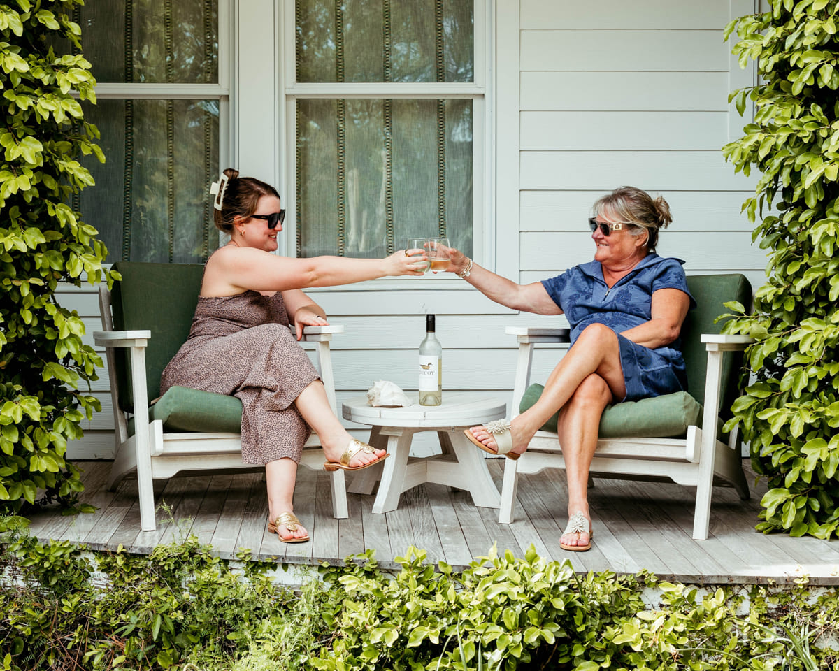 Two women toasting on porch, enjoying their Bourbon Patio Lounge Furniture.