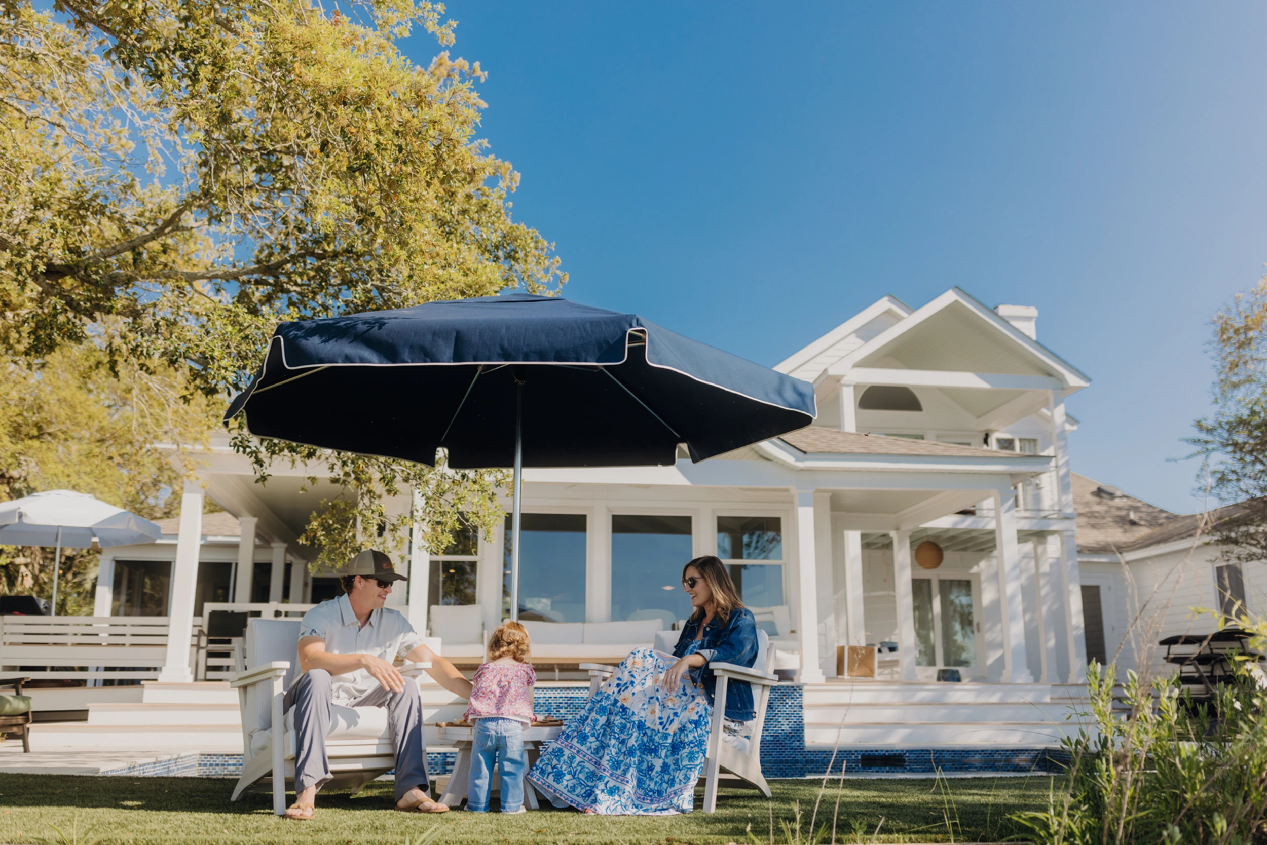 A family sits under a Palmetto umbrella enjoying a summer day