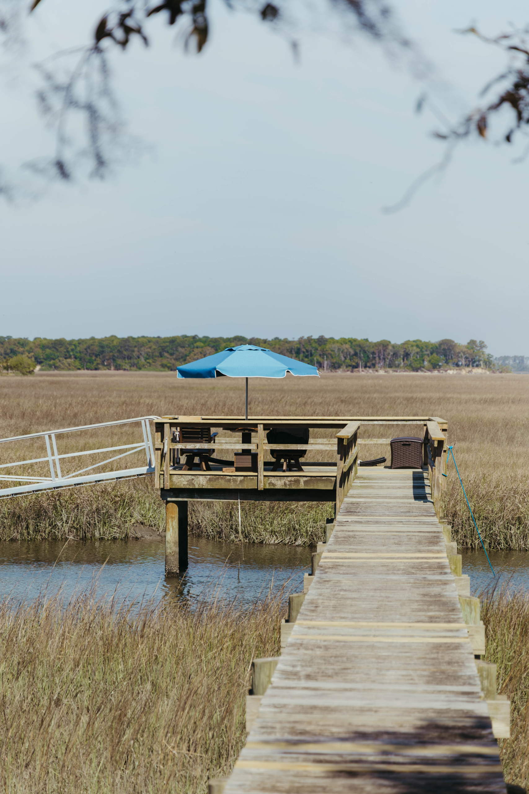 A Capri Blue Palmetto Umbrella on a long dock