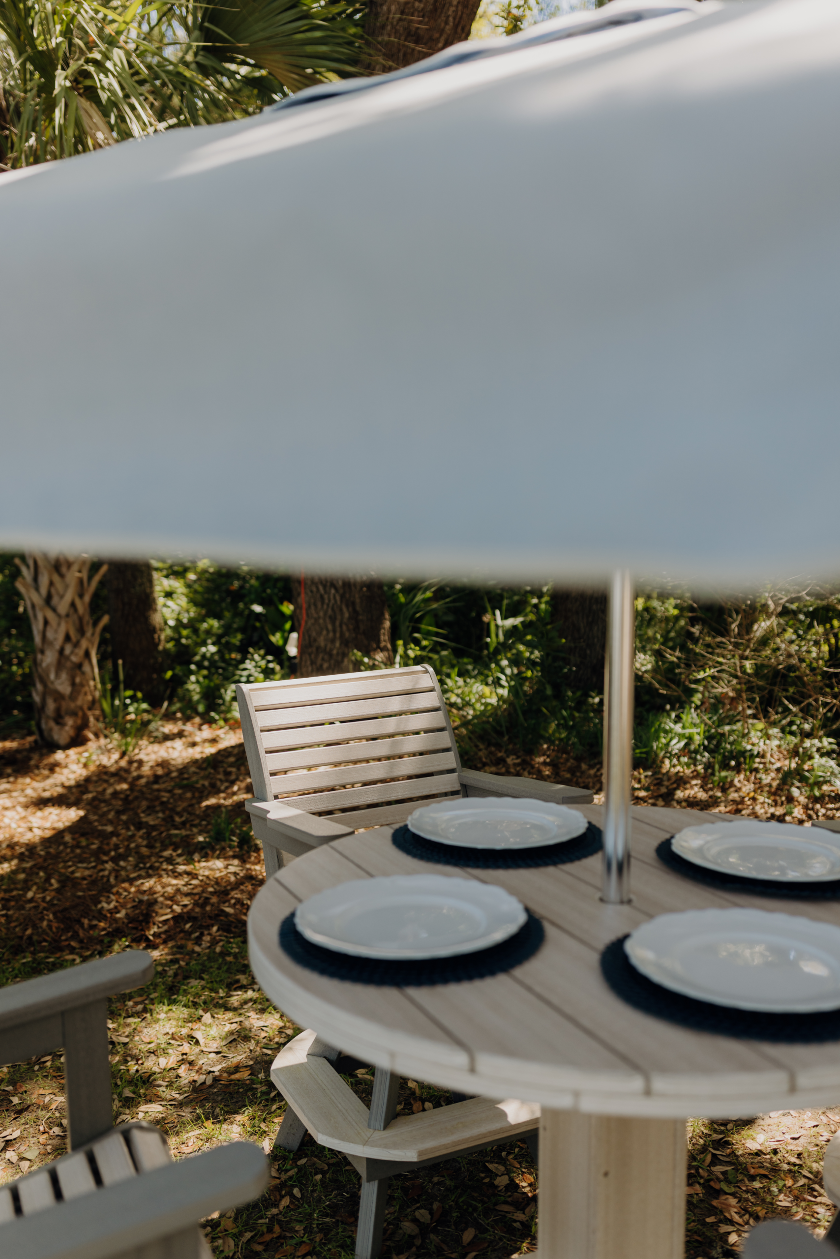 A Seashell Patio Furniture set perfectly arranged for dinner in the shade of a Palmetto Umbrella.