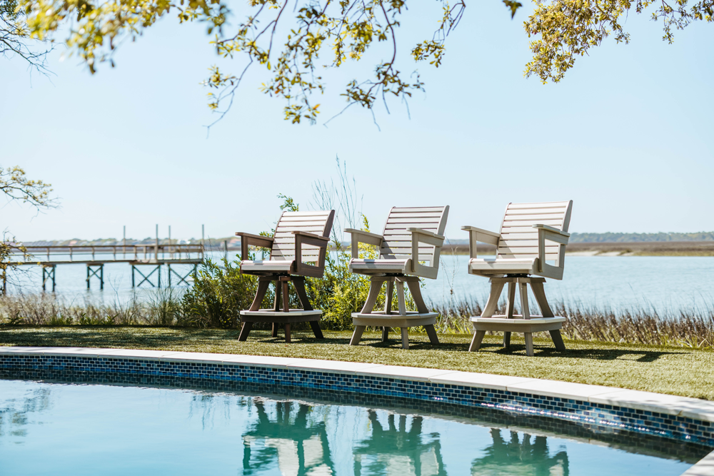 Three High Tide chairs in white, grey, and brown lined up beside the pool — easy, relaxed patio furniture style.