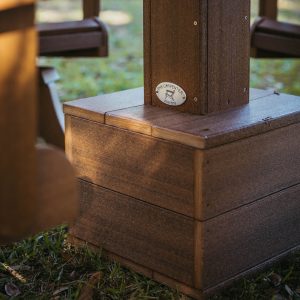 A Mahogany Box Anchor Outdoor Umbrella Base sits in the sun with an Ebb Tide Table above it. 