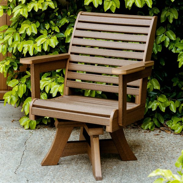 A Low Tide Chair sits on a concrete outdoor patio in front of a green leaf wall. 
