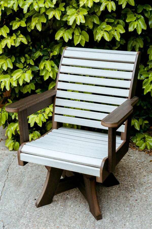 Seashell and Walnut Low Tide Outdoor Dining Chair rests on a concrete patio in front of greenery. 