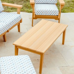 A Teak Sweetgrass Outdoor Coffee Table sits near a pool.  